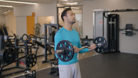 fit french man doing barbell bicep curls, building a bigger biceps brachii muscle as well as the brachialis