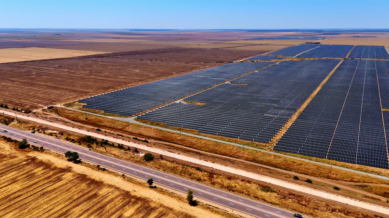 Solar farm under clear blue sky. Rows of solar panels stretch across vast fields, highlighting renewable energy use in agricultural landscapes