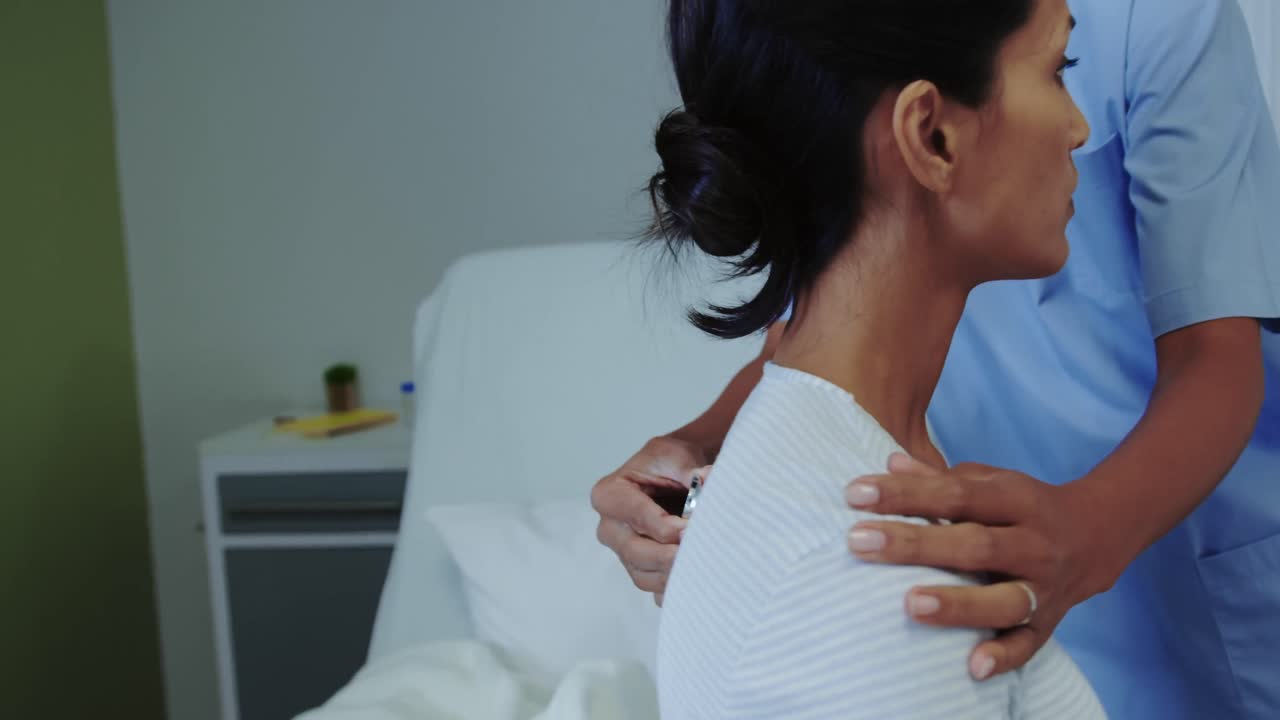 Close-up of African american female doctor examining female patient in the ward at hospital