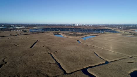 Aerial-view-of-a-tidal-marsh-approaching-a-solar-farm-in-Sayreville,-New-Jersey