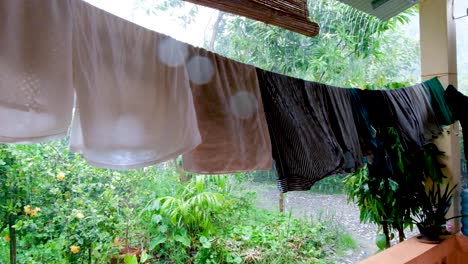 ropa mojada empapada en la línea de lavado durante la lluvia y las condiciones climáticas ventosas, ropa que sopla en el viento, gotas de lluvia en la lente de la cámara