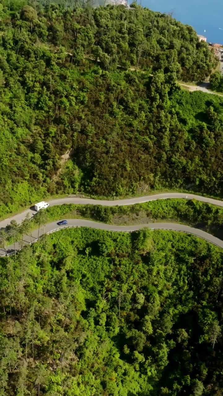 Toma de dron vertical girando lejos de una autocaravana circulando por una carretera de montaña en Italia