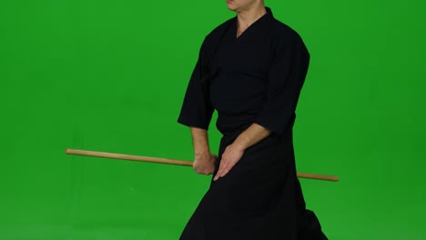 masculine kendo warrior practicing martial art with the bamboo bokken on green screen. close up