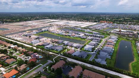 dolly out drone shot west palm beach construction site and residential area with lakes during the day in florida, usa