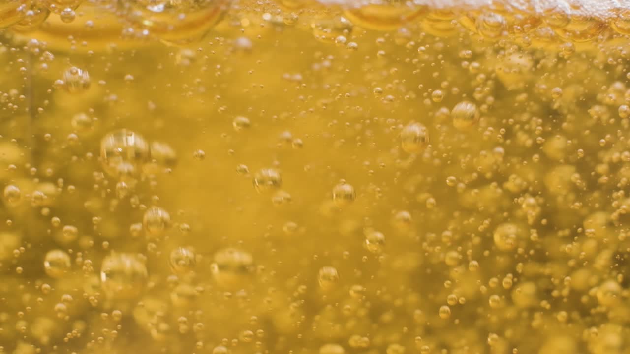 Extreme macro shot pouring beer on glass, Slow motion bubbles and foam texture