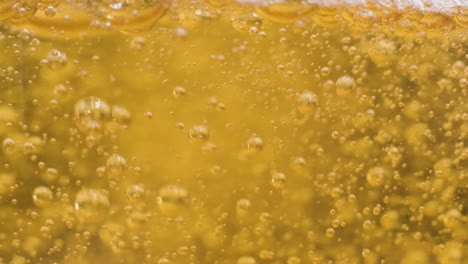 extreme macro shot pouring beer on glass, slow motion bubbles and foam texture