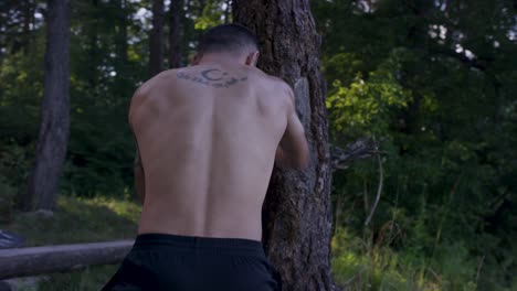 man training boxing outdoors against a tree