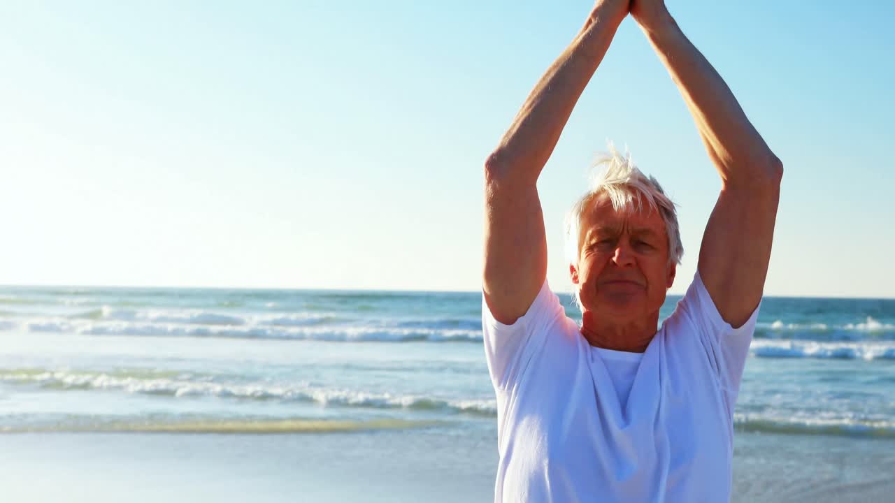 Uomo anziano che fa yoga in spiaggia