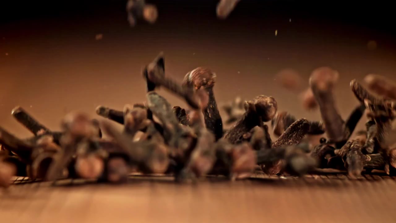 Close-up de Cravos-da-Índia Caindo sobre uma Superfície de Madeira em Câmera Lenta