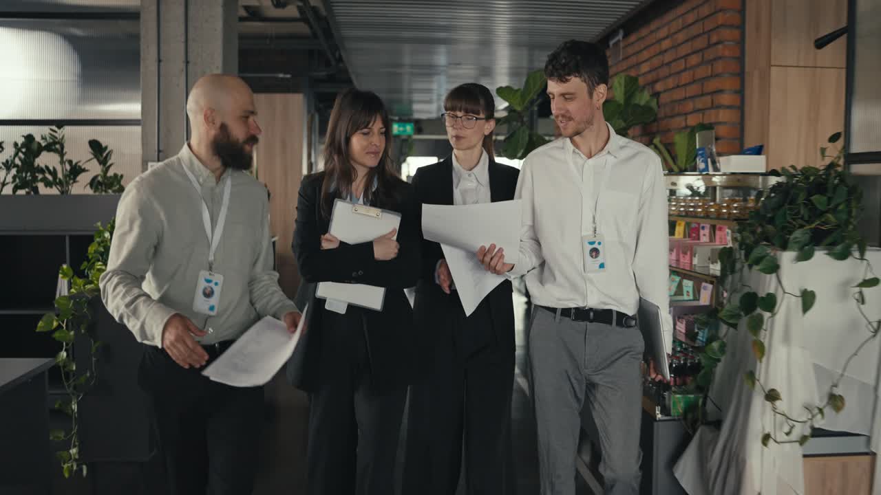 Group of business people walking and discussing work in an office hallway