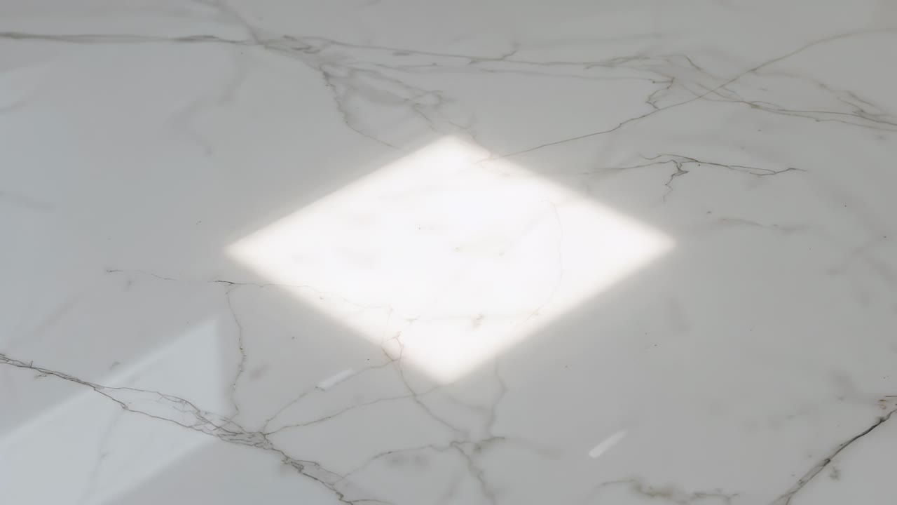 Formazione di una macchia solare a forma di diamante che scivola su una superficie di marmo mentre la luce del sole filtra attraverso l'ombra della finestra