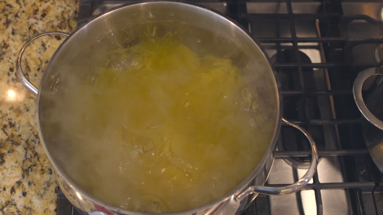 Overhead view of pasta in a pot of boiling water on a stove top in a kitchen