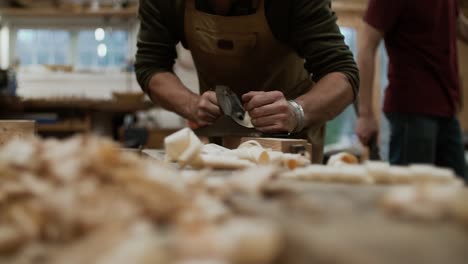 Closeup-with-a-man-working-with-handheld-plan-in-slow-motion-shaping-the-wood