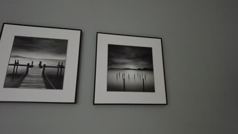 two grey paintings and a grey clock artfully arranged on a monotone wall, creating an intriguing display of minimalistic aesthetics