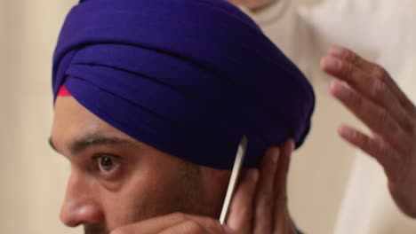 Nahaufnahme-Einer-Studioaufnahme-Von-Zwei-Sikh-Männern,-Die-Beim-Aufsetzen-Eines-Turbans-Vor-Einfachem-Hintergrund-Eine-Salai-Nadel-Verwenden-2