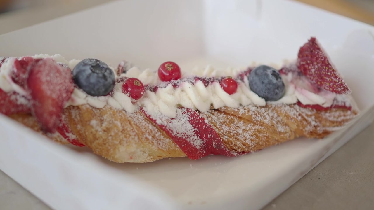 Pasticcino fresco guarnito con panna e frutti di bosco in una scatola di carta