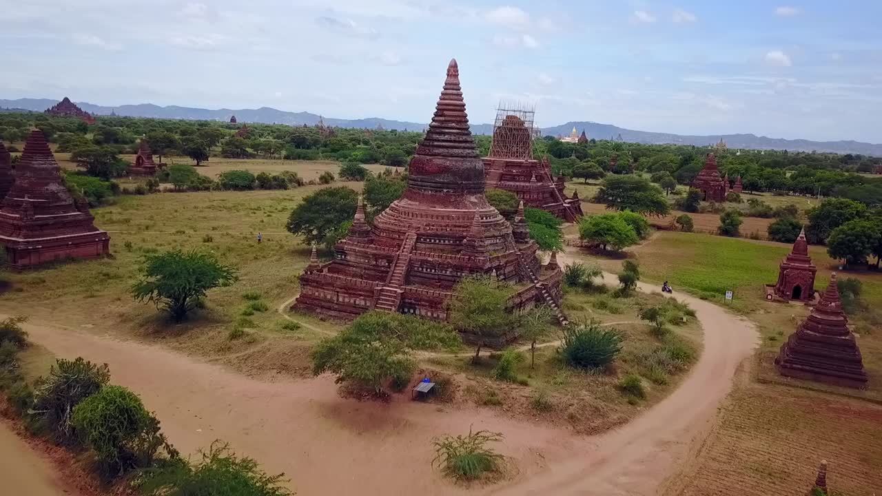 A low aerial drone shot unveils the intricate design of Bagan’s First Temple, crafted from red brick and surrounded by verdant greenery. A close look at Myanmar’s architectural heritage