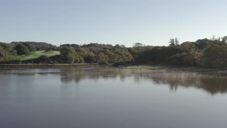 serene aerial flight over river mist toward natural green shoreline