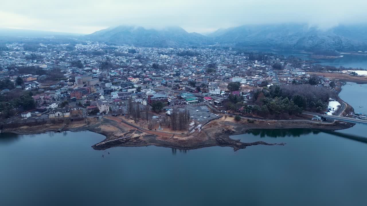 Toàn cảnh trên không chụp bằng drone của thị trấn Fujikawaguchiko với những con đường ngoại ô và khách sạn thương mại bên cạnh hồ, cùng những ngọn núi rừng phủ sương mờ ảo nơi chân trời, tại Yamanashi, Nhật Bản, Châu Á. Cơ sở hạ tầng, du lịch.