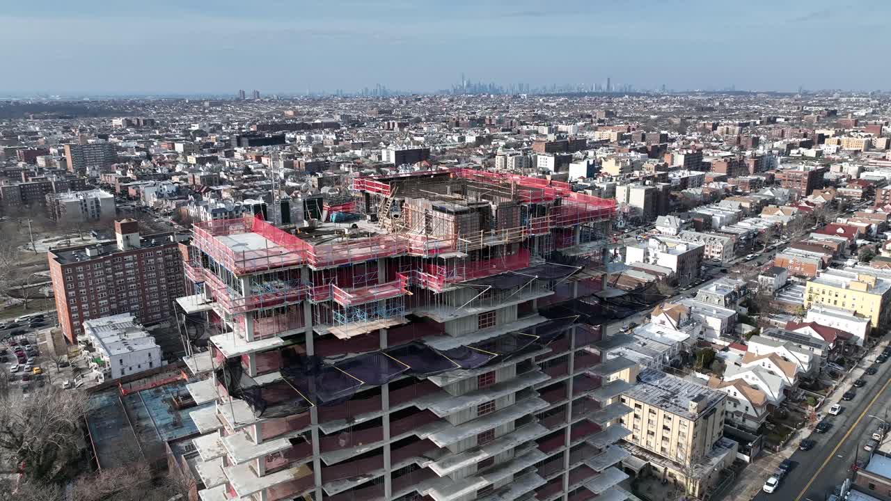 una vista de ángulo alto sobre un edificio, aún en proceso de construcción en brooklyn, ny con nyc y verrazano en la distancia