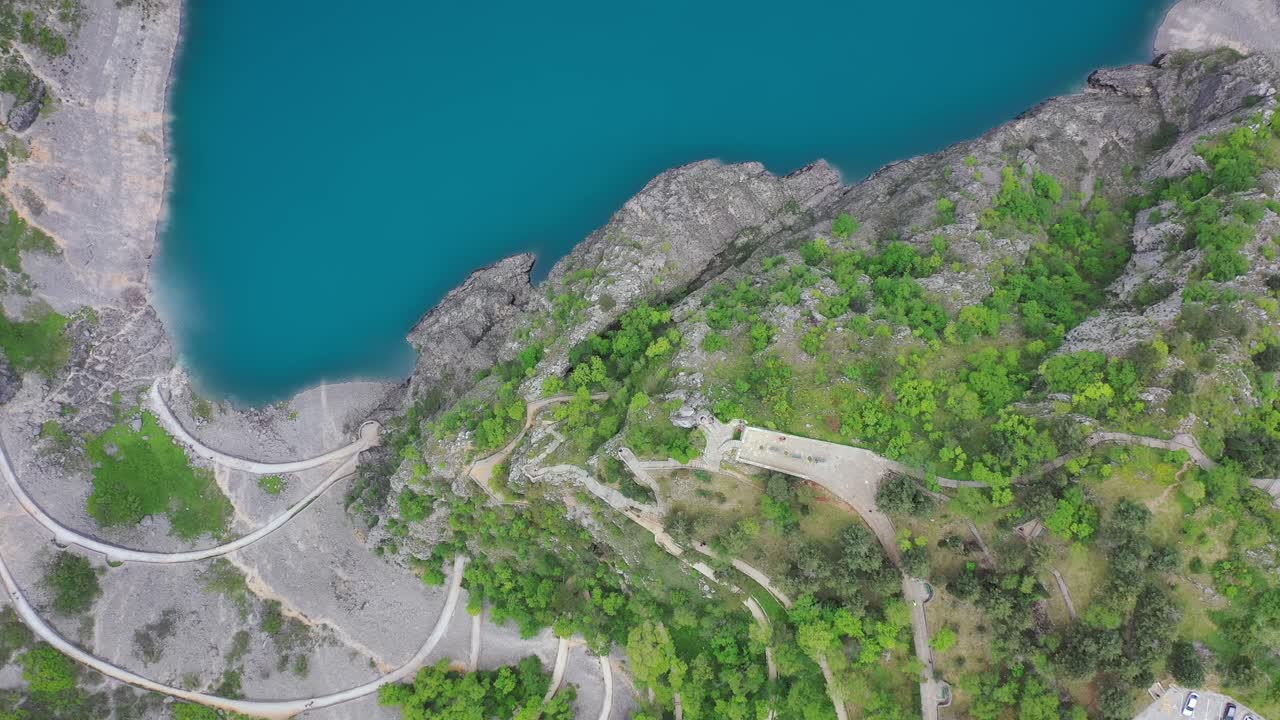 top down aerial view of meandering road towards blue lake, Imotski, Croatia