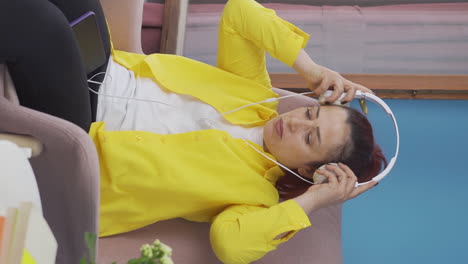 Vertical-video-of-Unhappy-woman-listening-to-music-with-headphones.