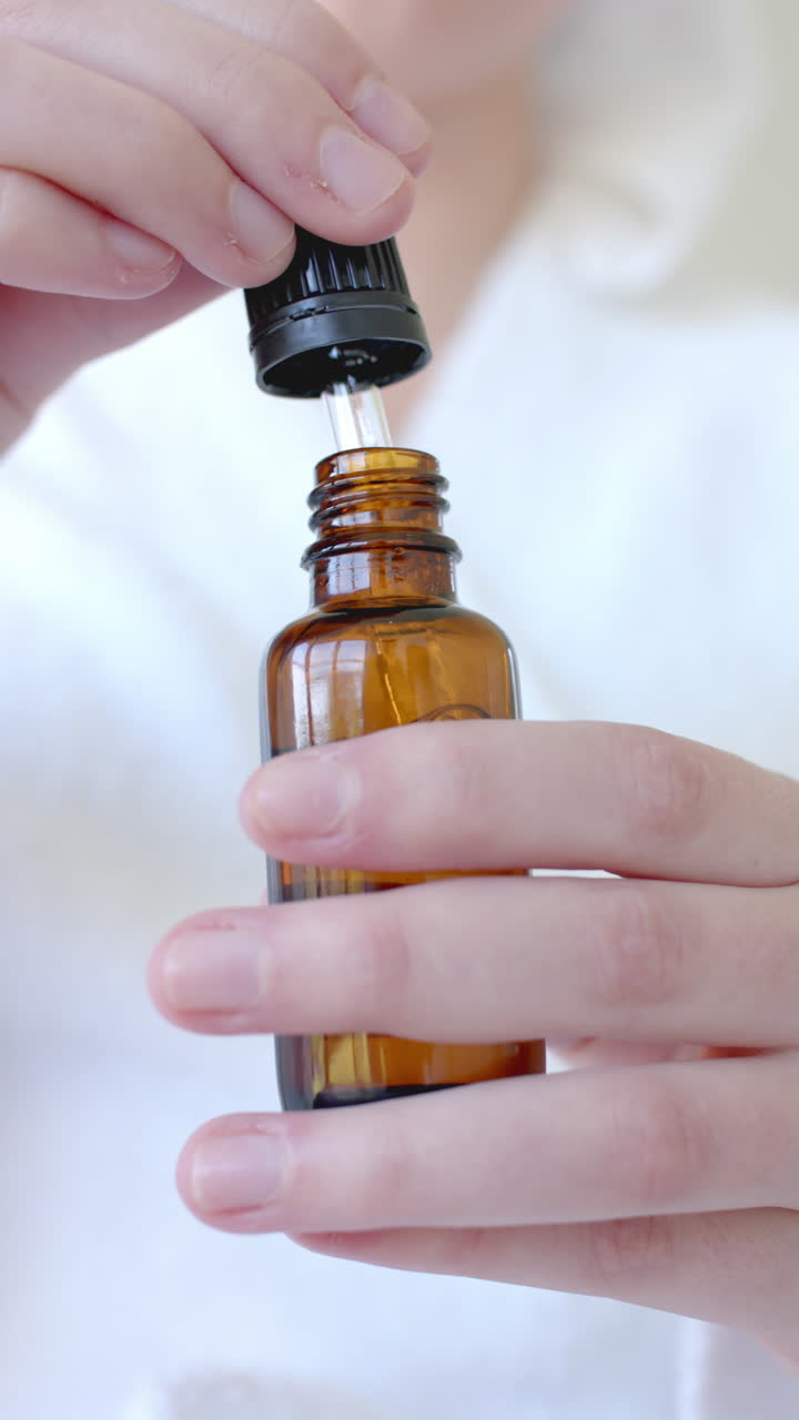 Vertical video of caucasian woman taking sample of oil in bathroom in slow motion