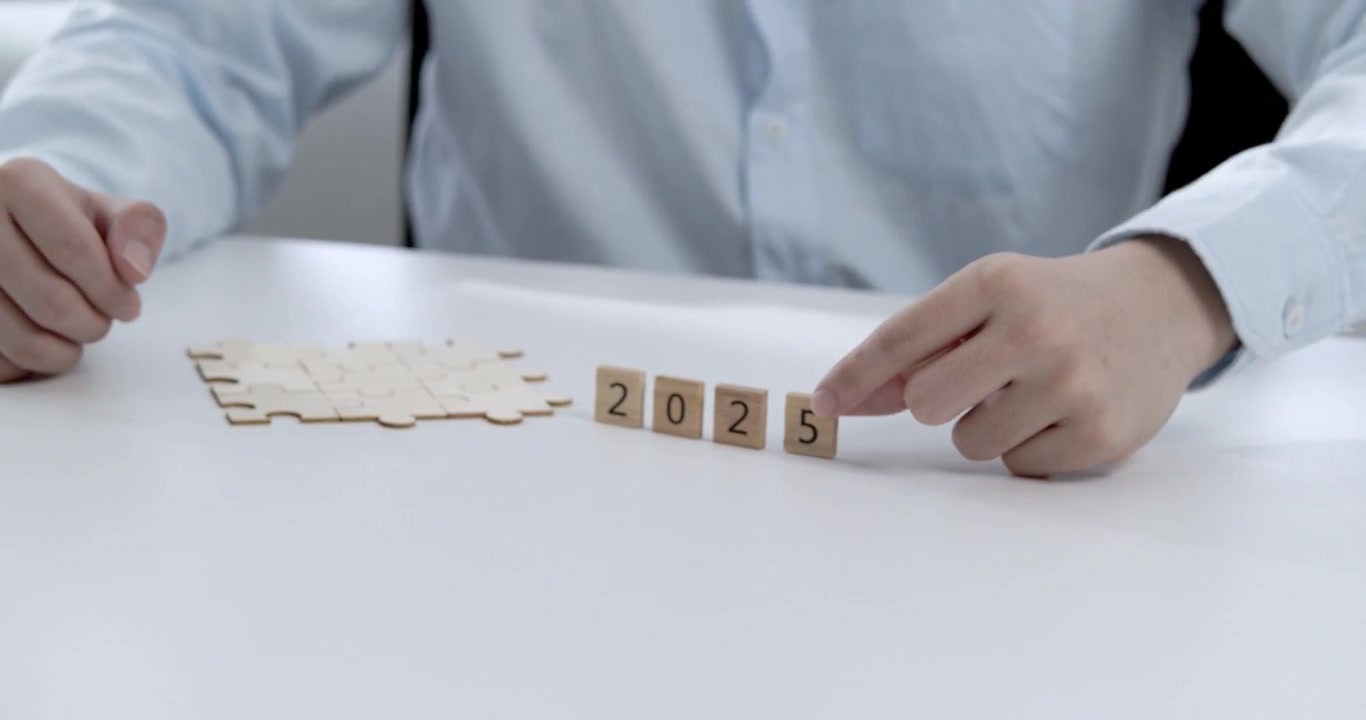 Mano de un joven oficinista colocando el número de madera 5 para actualizar el año a 2025, simbolizando la planificación del éxito empresarial y los objetivos de logro con piezas de rompecabezas de madera