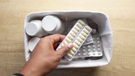 person taking pills from a container.