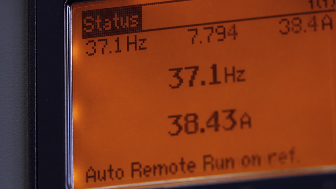 A close-up of an orange industrial digital control panel shows its LED screen adjusting numeric readouts, highlighting precise calibration in real time