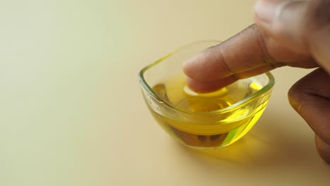 una persona sumergiendo su dedo en un cuenco de aceite de oliva