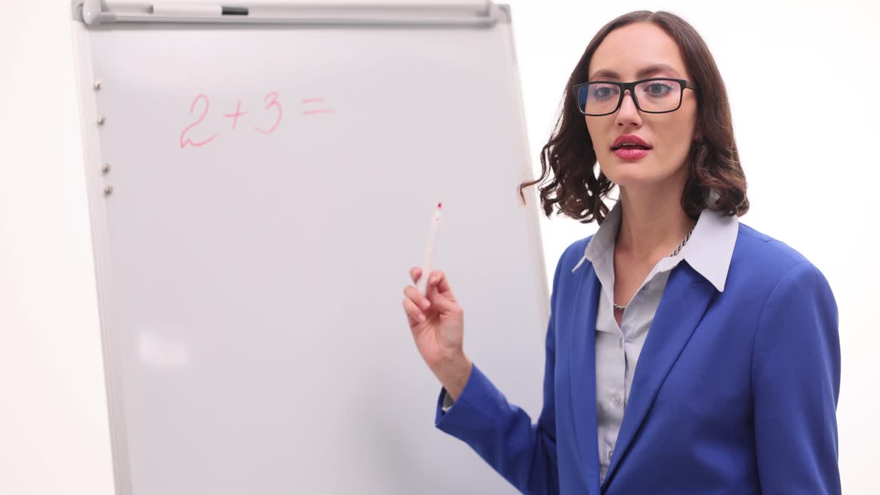 A teacher explains a math problem on a whiteboard
