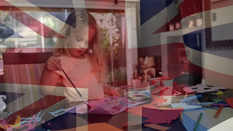 Animation-of-flag-of-uk-flag-over-happy-caucasian-girl-painting-at-home