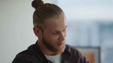 Positive-man-talking-at-evening-office-portrait.-Bearded-developer-communicating