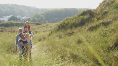 multi-generation family walking along path through sand dunes together