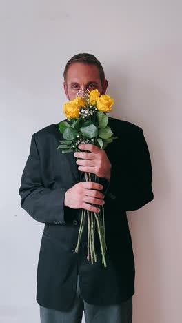 hombre en un traje negro sosteniendo rosas amarillas