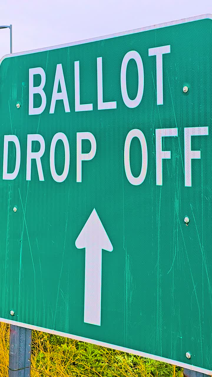 Vertical video of an official election sign reading “Ballot Drop Off” with a bold arrow directs voters beside a road, symbolizing freedom, safety, civic engagement, responsibility, democratic voting