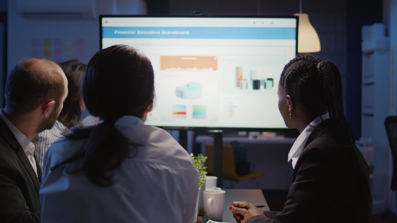 Businesswoman explaining financial graphs using presentation monitor overworking in office