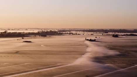 endless flatlands of netherlands covered in rising fog, aerial cinematic view