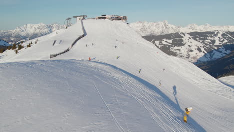 people skiing in a snowy mountain ski resort in saalbach-hinterglemm, austria - drone shot