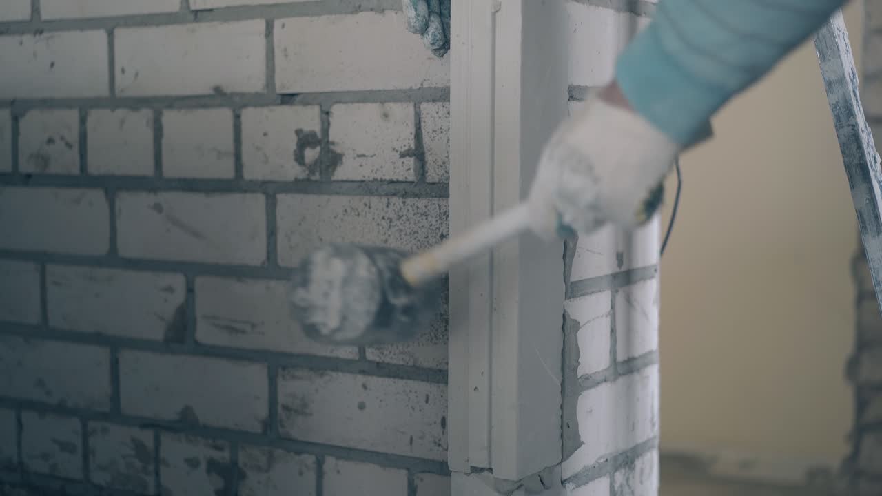 한 남자 가 망치 로 벽 에 지프스 판 을 손 으로 고정 시키고 있다