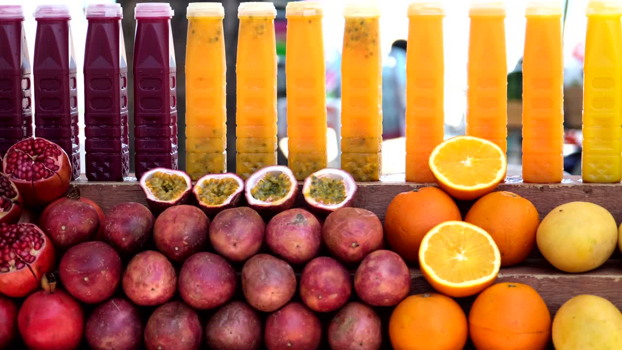 una exhibición de coloridos jugos de granada y naranja con las frutas reales debajo de las exhibiciones