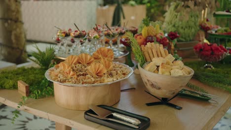 luxurious outdoor buffet table with cheese platter breadsticks fruit and layered dessert cups at wedding or upscale event