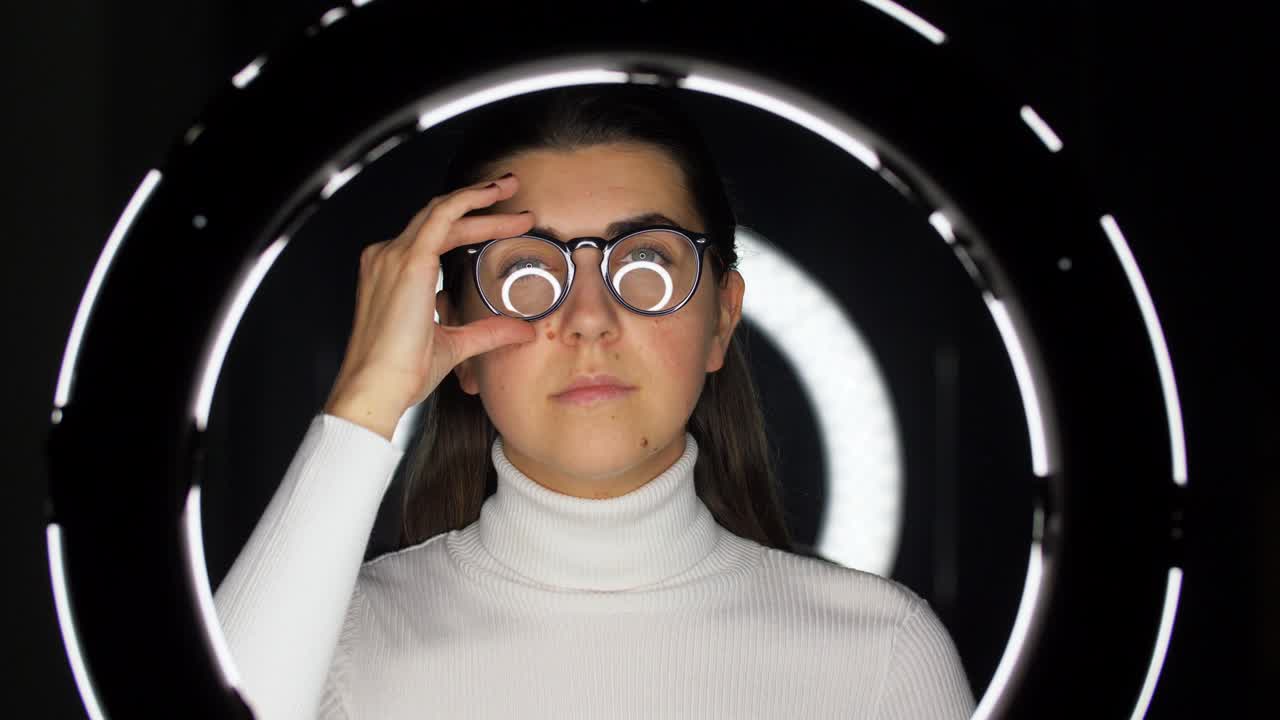 mujer con gafas sobre iluminación blanca en negro