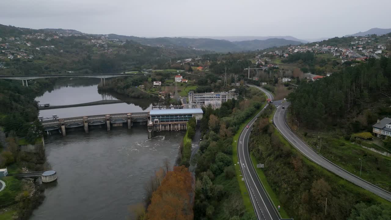 Flyover above highway road lining river by Velle water dam and power plant in Ourense, Galicia, Spain