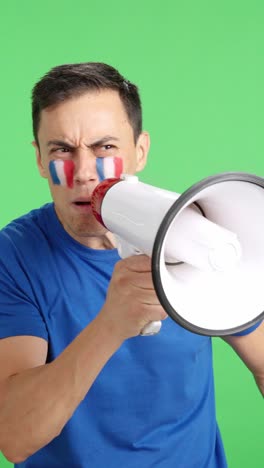 excited man with french flag on face using a megaphone