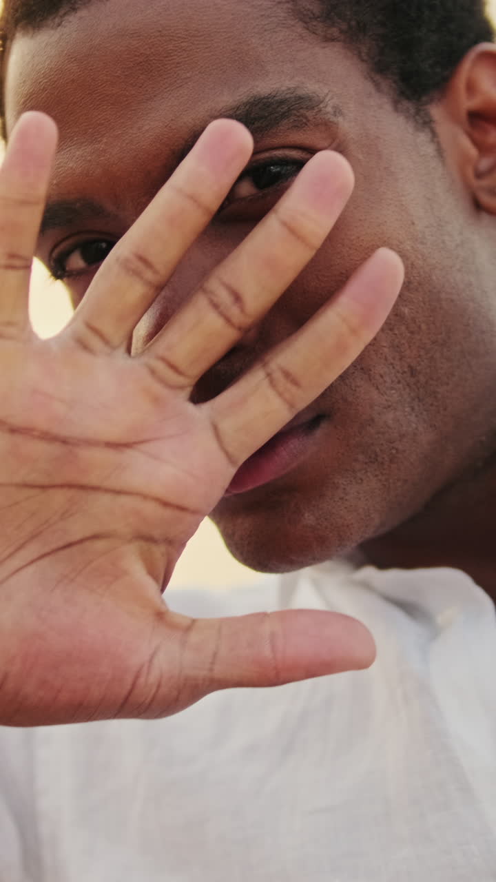 Giovane uomo afroamericano che si copre il viso con la mano e sbircia