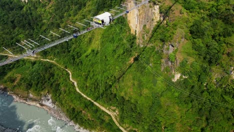 Luftaufnahme-Eines-Bungee-Jumpings-Auf-Einer-Brücke-In-Nepal-Bei-Sonnenuntergang-Von-Oben-Nach-Unten---Filmischer-Drohnenflug-über-Den-Fluss