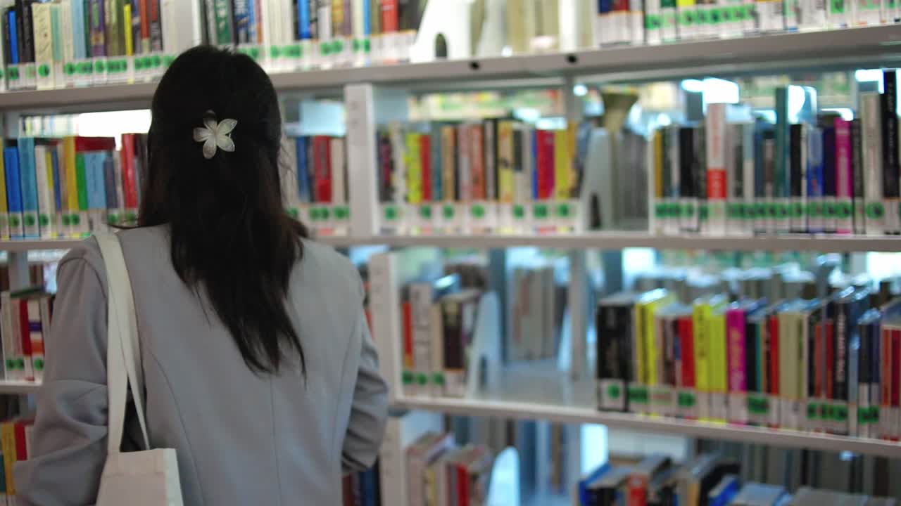 Donna che sfoglia i libri in una biblioteca