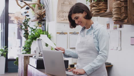 Asistente-De-Ventas-Femenina-Trabajando-En-Una-Computadora-Portátil-Detrás-Del-Mostrador-De-Ventas-De-Una-Floristería